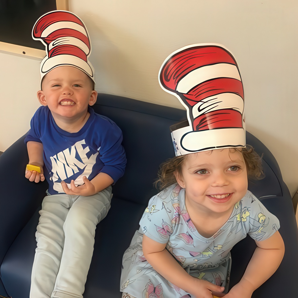Kids in Cat in the Hat hats smiling on a couch.