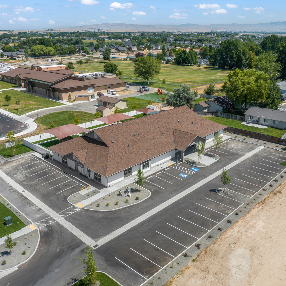 Aerial view of building, parking lot, and surrounding area.