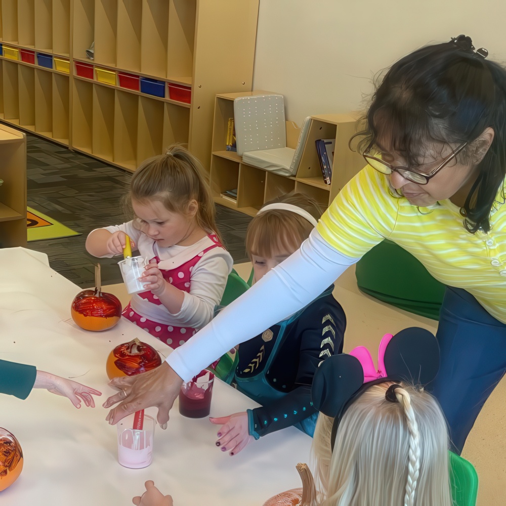 Teacher helps kids with a colorful classroom science project.