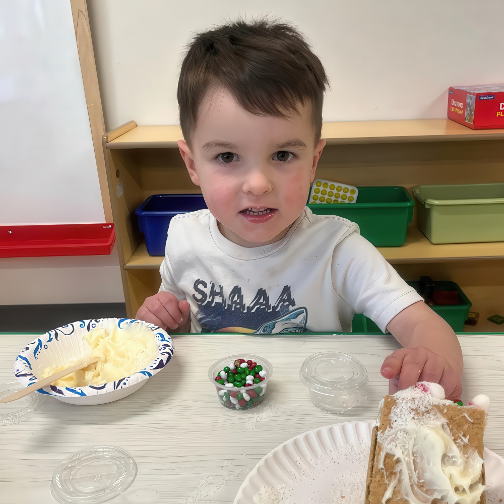 Child decorating gingerbread house with candy and frosting.