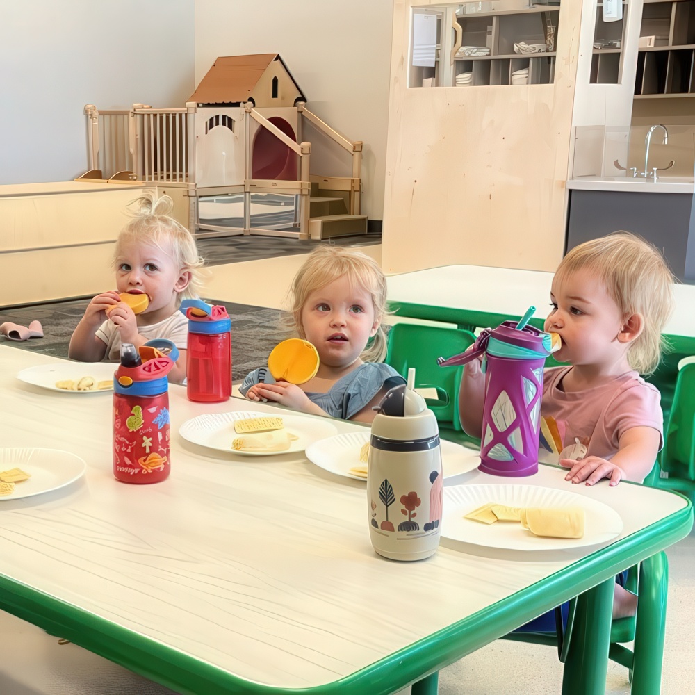 Toddlers eating snacks together at a table.