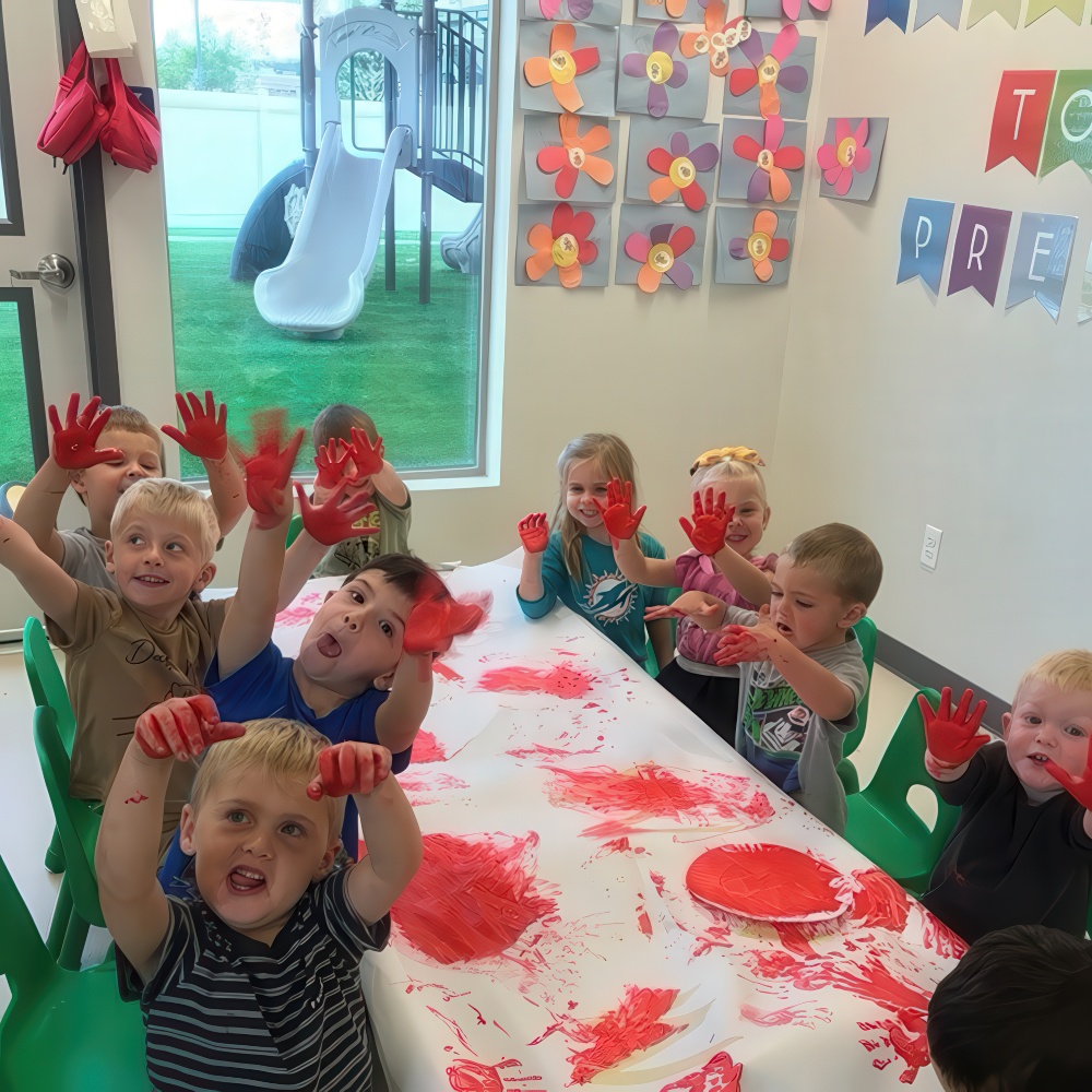 Kids with red paint on hands smiling during art activity.