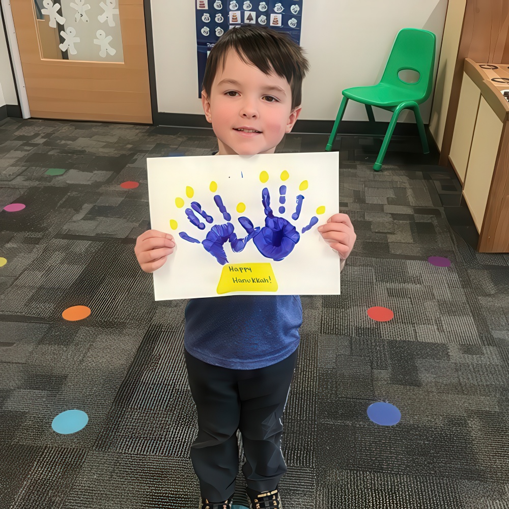 Child proudly shows a handprint art project.