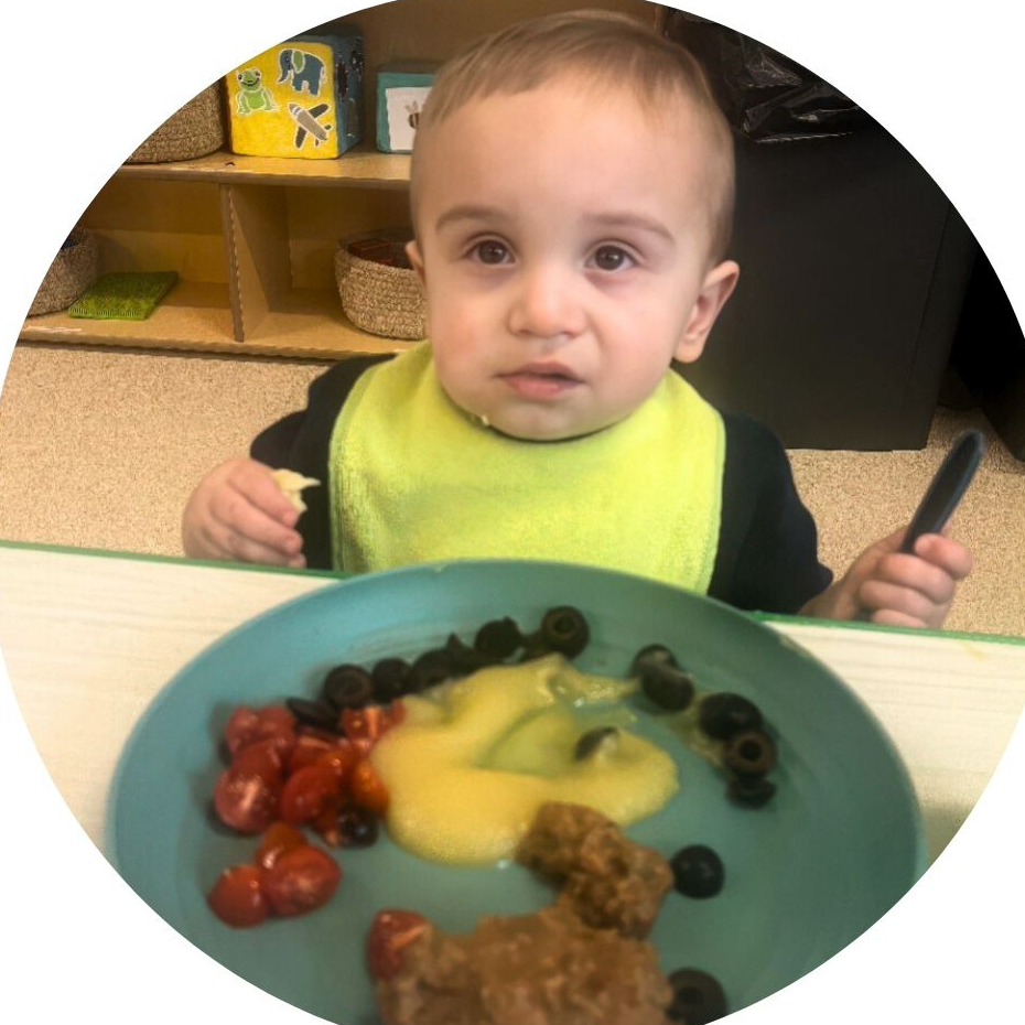 Young child enjoys a meal with veggies and fruit.