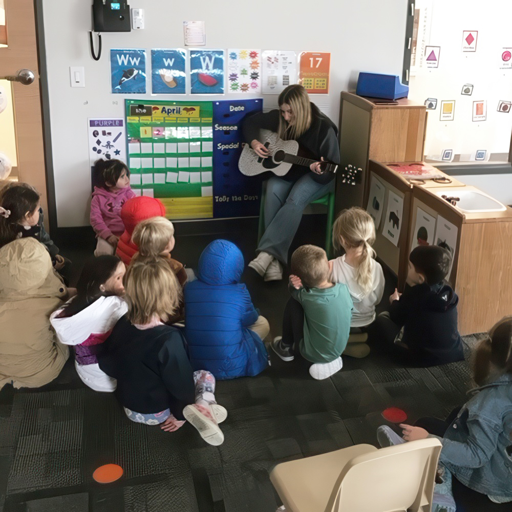 Teacher plays guitar for children during group time.