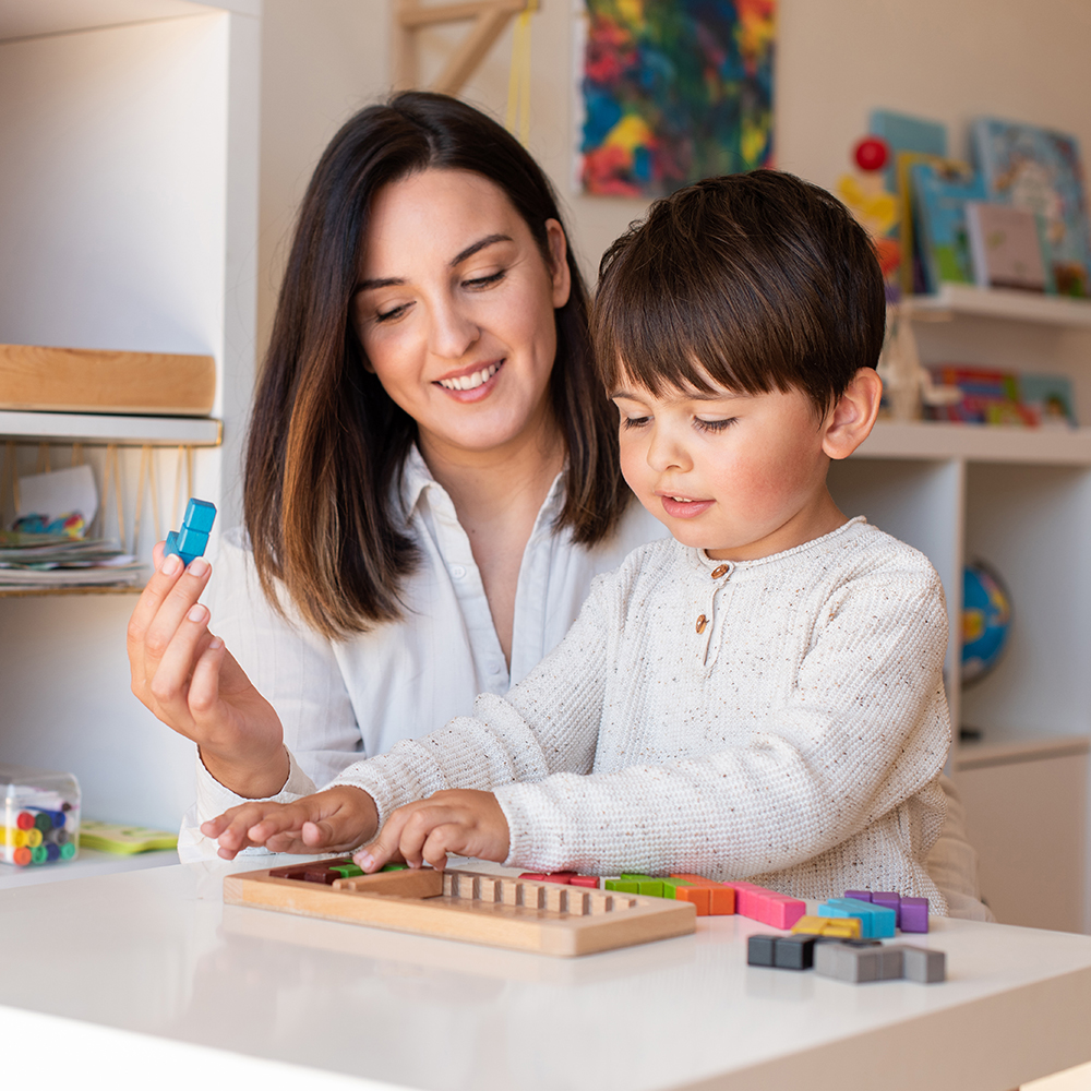 Teacher helps child build with colorful wooden blocks.