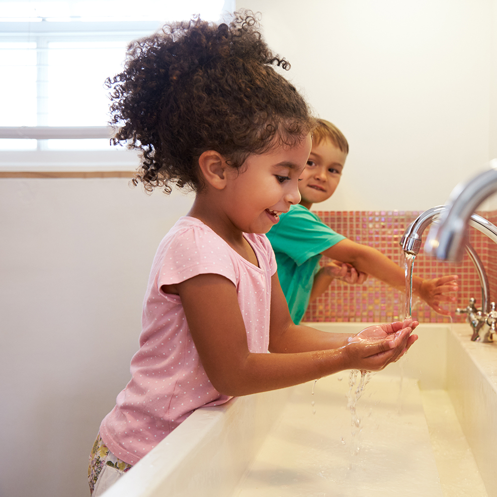 Children wash hands at the sink, enjoying water play.