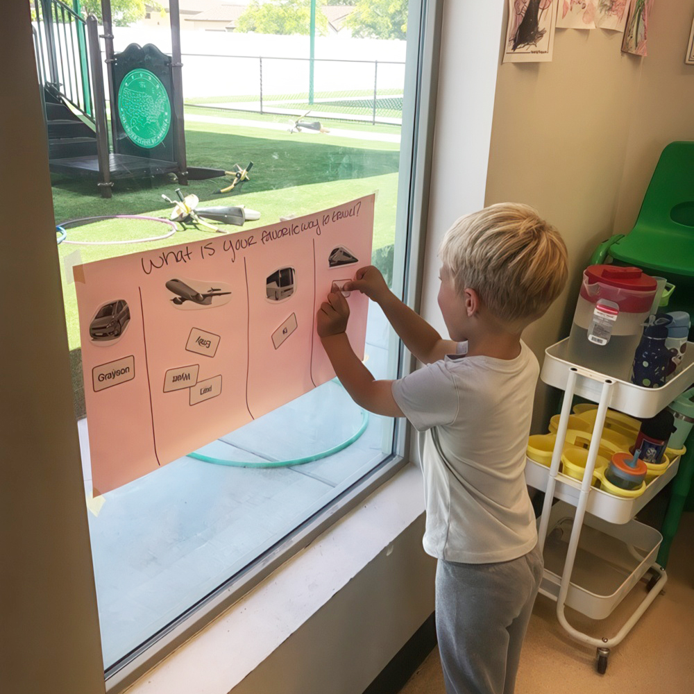 Young boy places a choice card on a favorite travel chart.