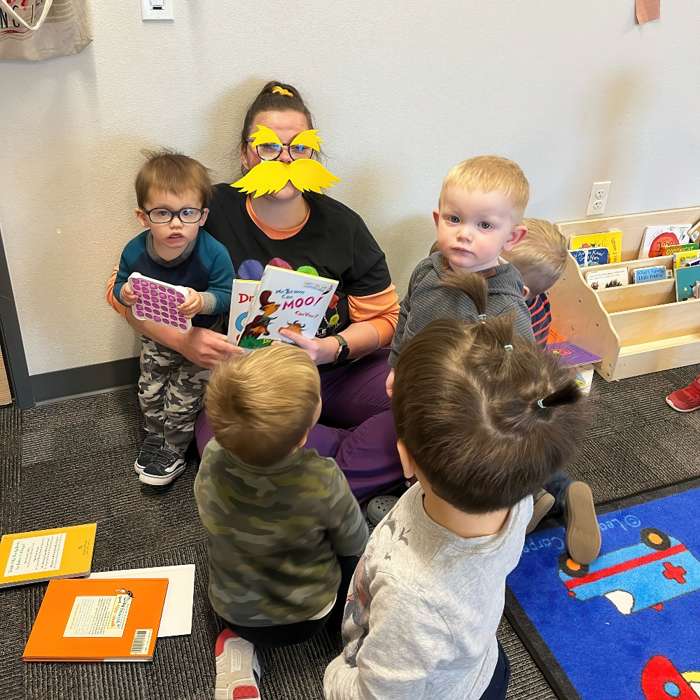 Teacher reads Dr. Seuss to toddlers gathered for storytime.