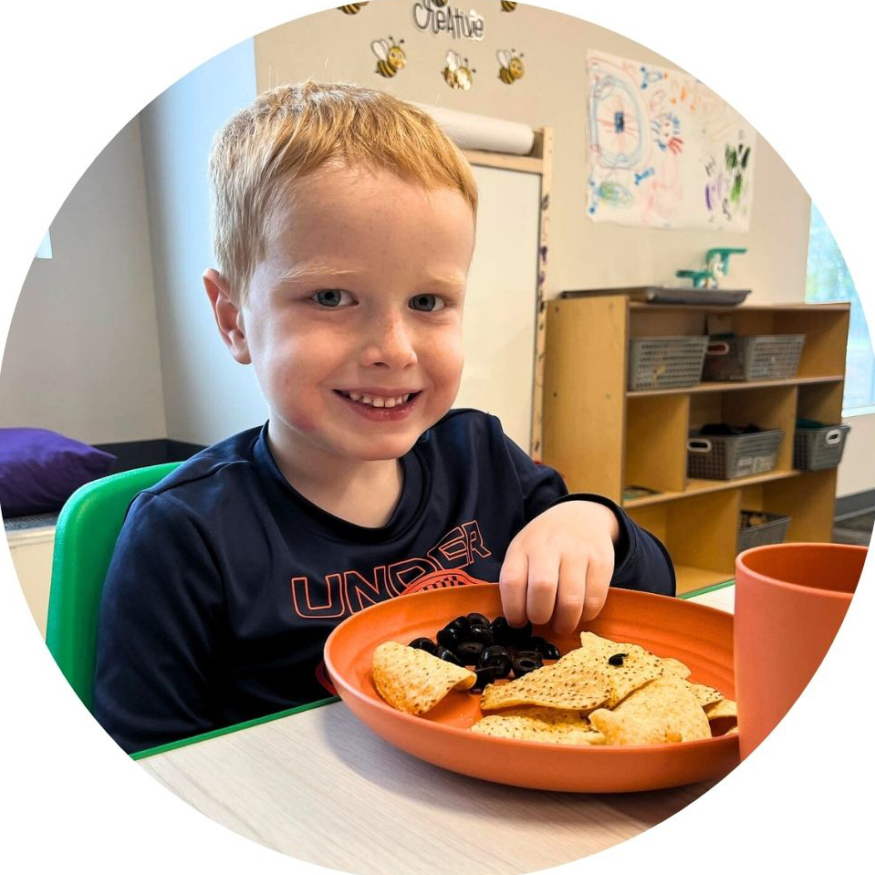 Child enjoys snack time with chips and olives in class.