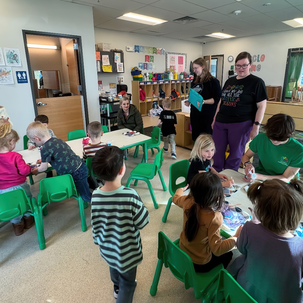 Teachers guide children through activities in a busy classroom.